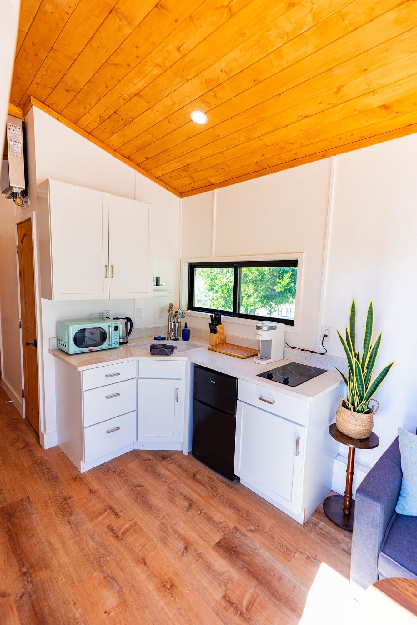 Kitchen corner with white cabinets, a microwave, a fridge and a stovetop