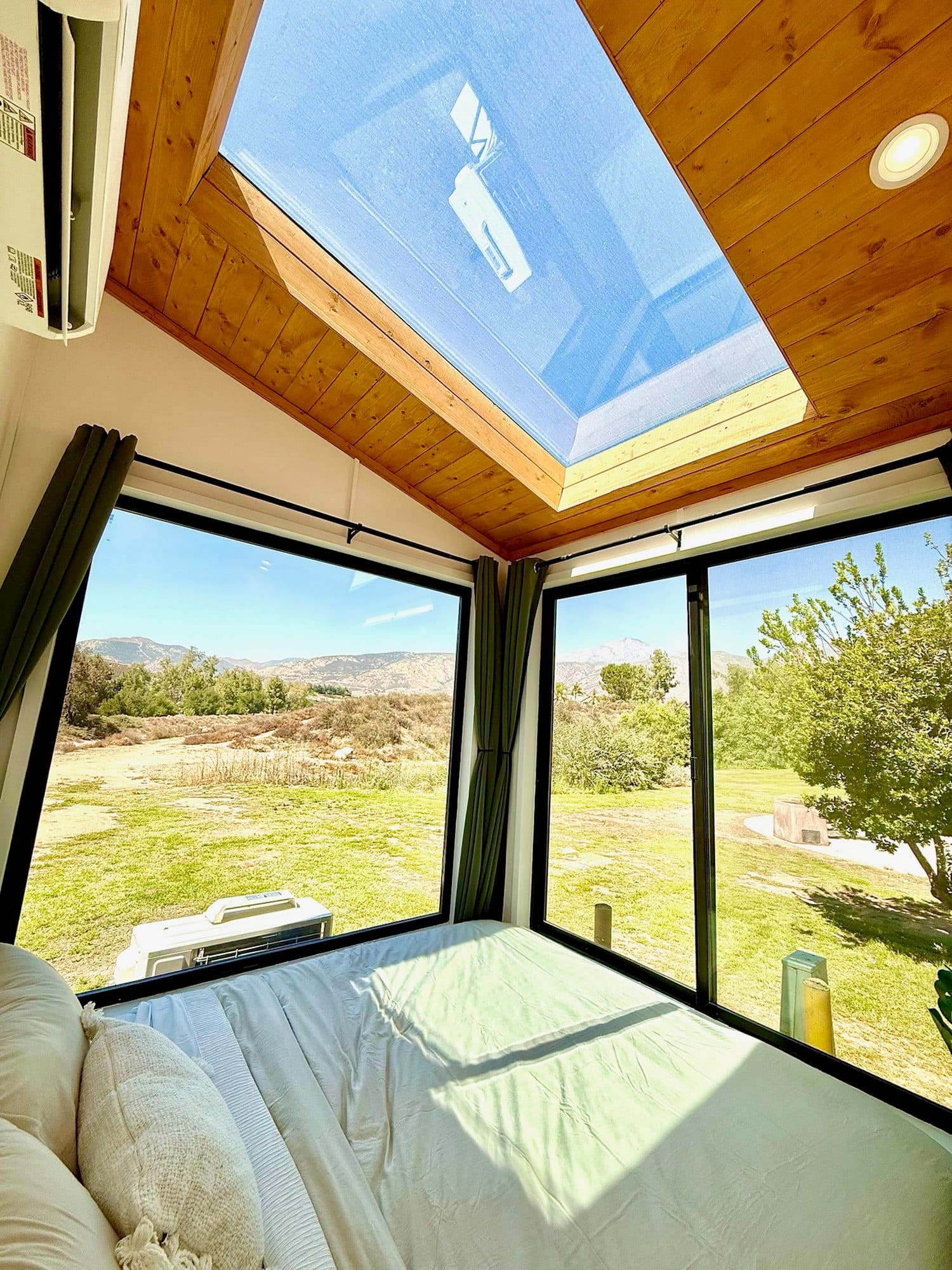 The bed under the skylight, with corner windows looking out at the park
