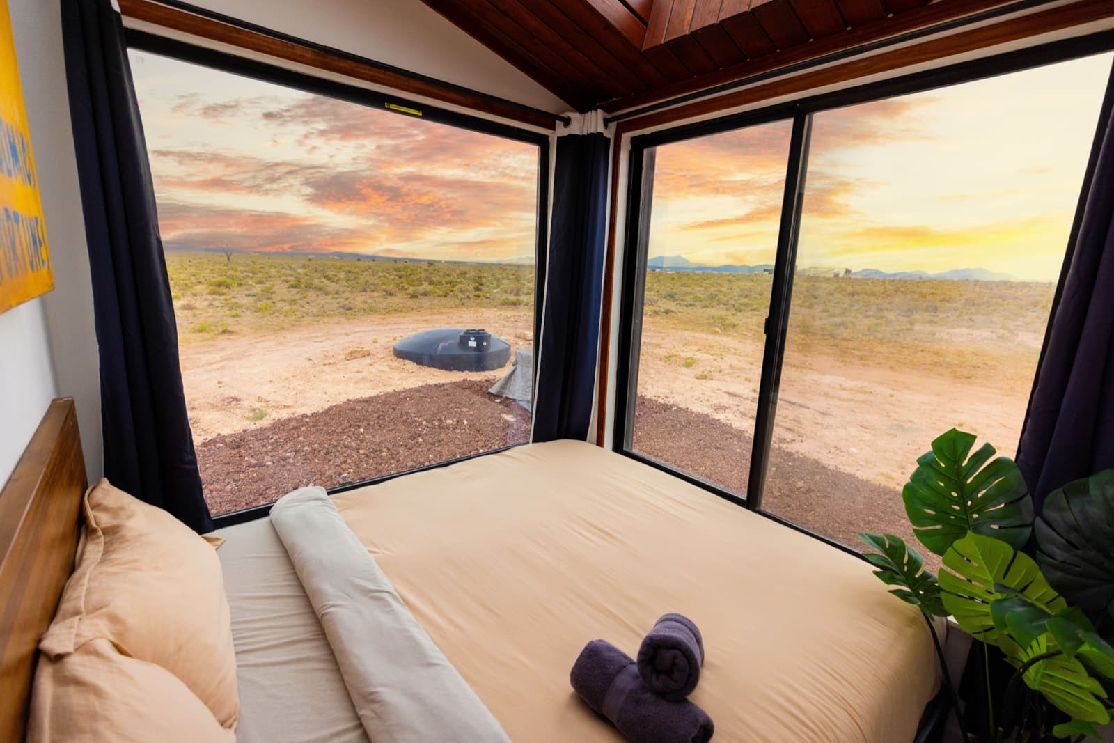 King bed facing two walls of windows at sunset