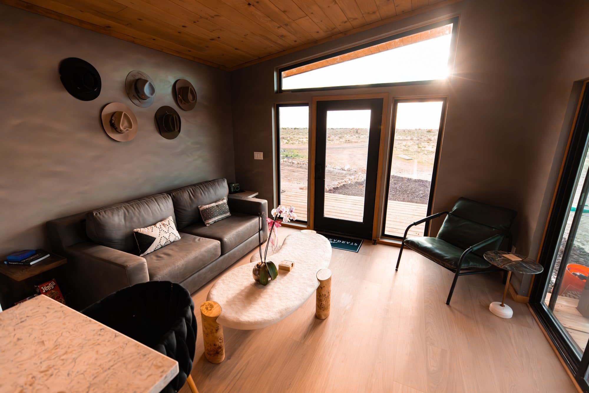 Living room with a leather sofa, hats on the wall and glass doors