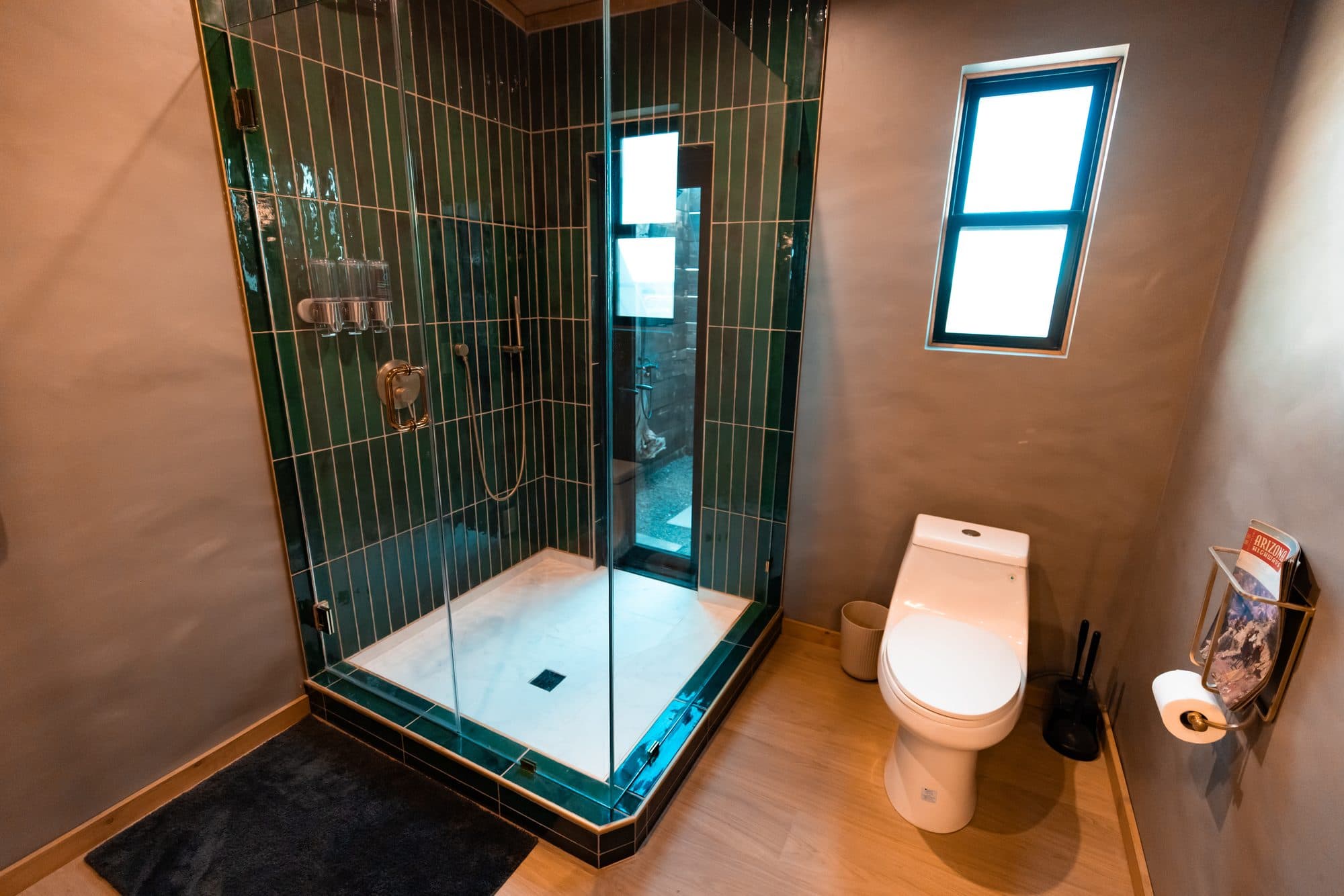 Glass shower with green tile, next to the toilet