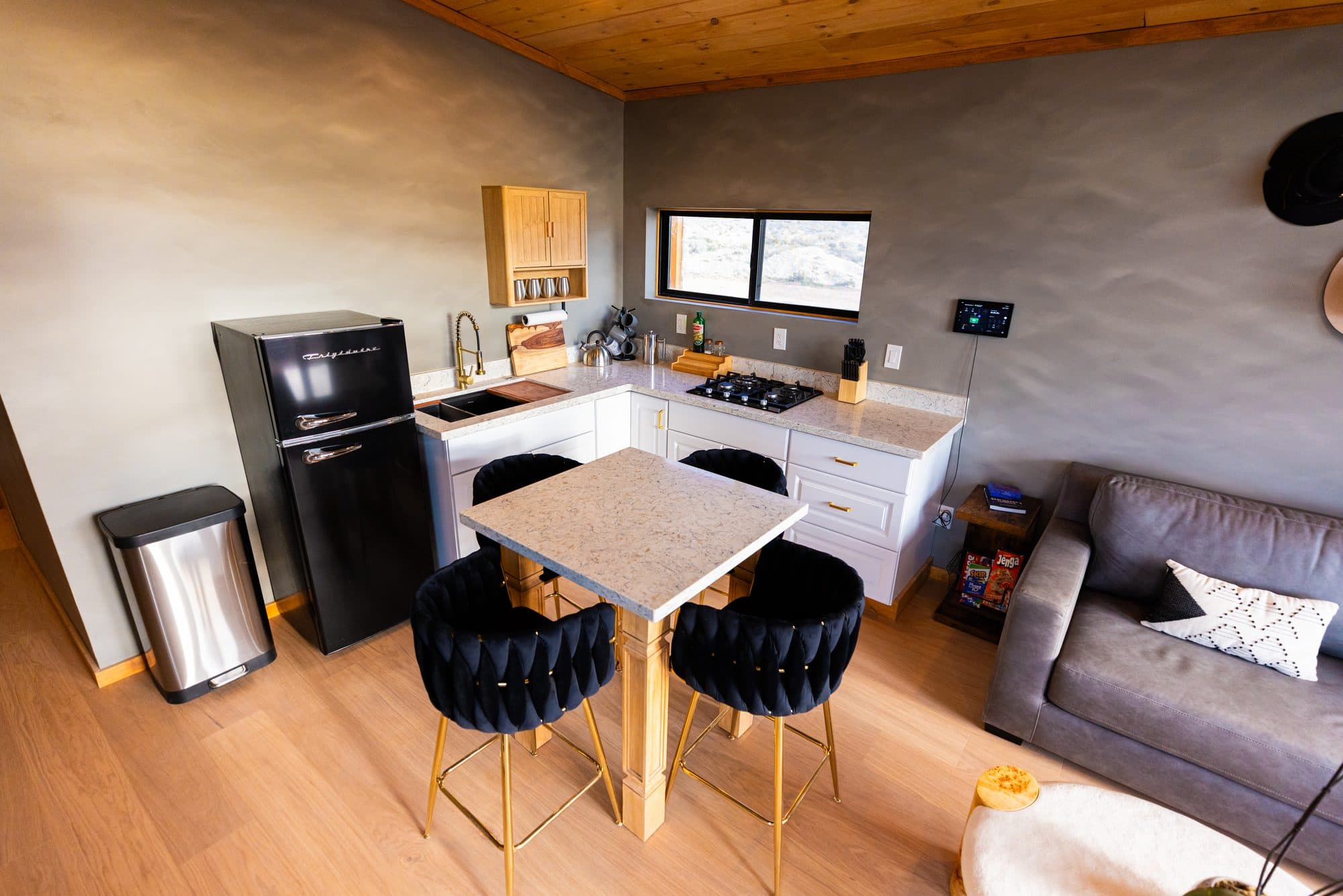 Kitchen with white cabinets, a black fridge and a small dining table